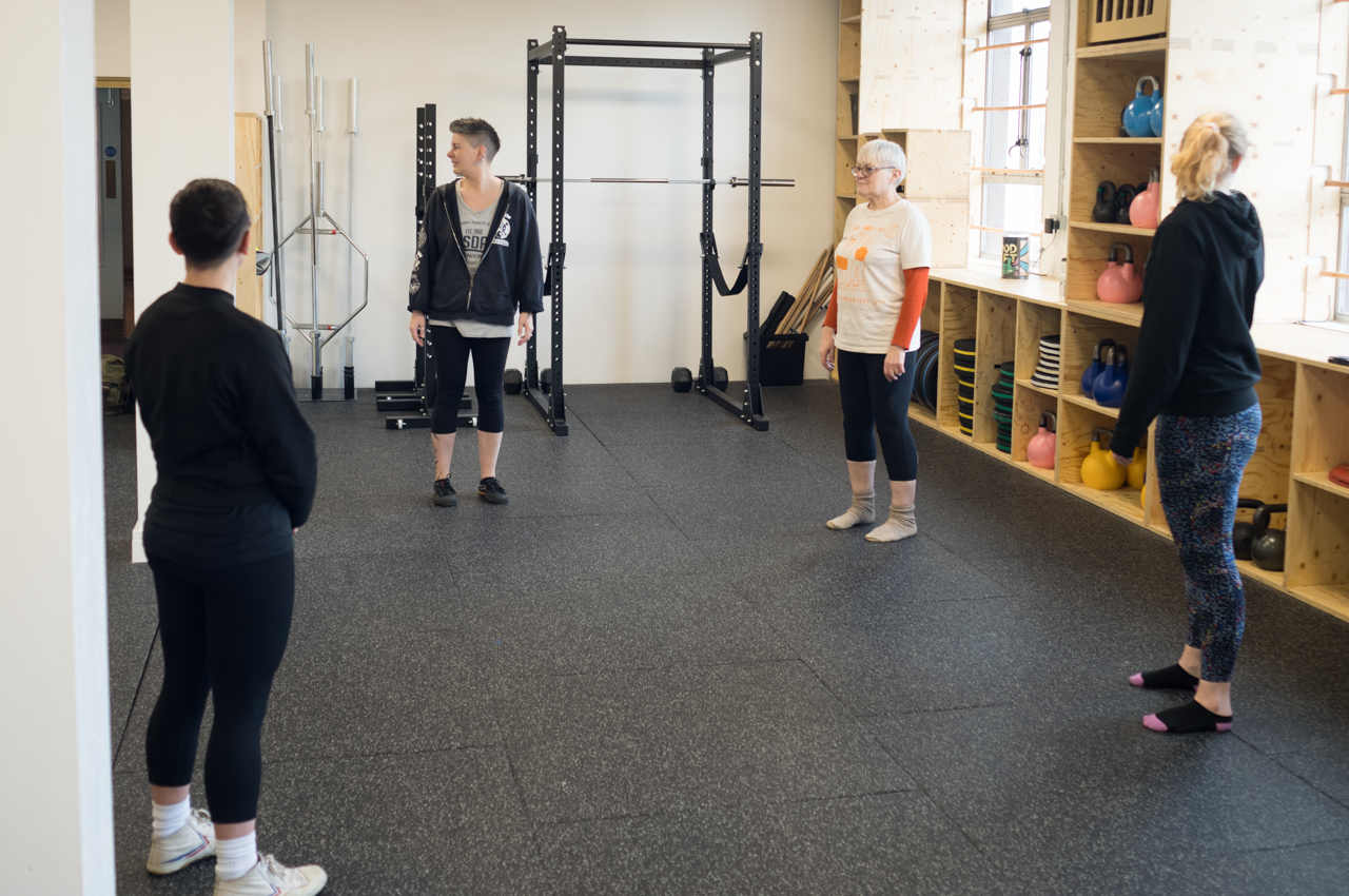Photo of four people in a gym, doing a warm up before exercising.
